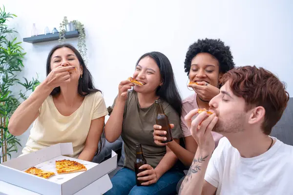 A group of friends enjoy pizza and beer in a comfortable home setting, sharing laughs and good food
