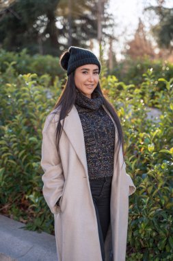 İyi giyimli bir kadın, şehir parkında canlı sonbahar yaprakları arasında sakin bir yürüyüş yapmaktan hoşlanıyor..