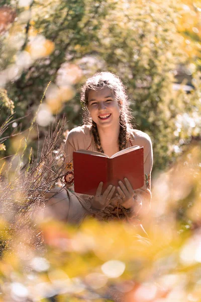 Güneşli bir günde açık havada kitap okurken gülümseyen mutlu genç adam..