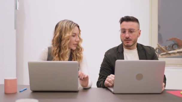 男性と女性の同僚がデスクでラップトップの作業を議論し 焦点を当てた表現 — ストック動画