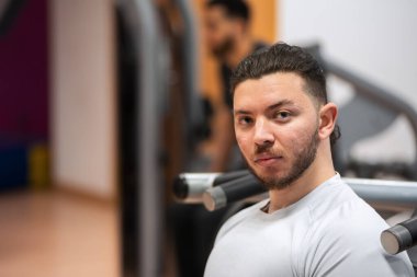 Beyaz tişörtlü genç adam spor salonunda yoğun bir idmana hazırlanıyor.. 