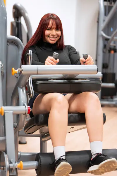 フィットネスセンターで脚プレス機を使用して輝く笑顔を持つ幸せな若い女性 ストック画像