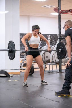 Kendini işine adamış bir bayan sporcu, antrenörüyle birlikte modern bir spor salonunda kaldırma egzersizine başlıyor.. 