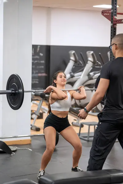 Focused Young Woman Performing Barbell Squat Guidance Male Trainer Gym Stockbild