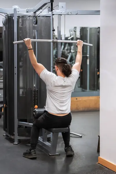 Bertekad Pria Melakukan Latihan Penarikan Lat Gym Dengan Fokus Pada Stok Foto
