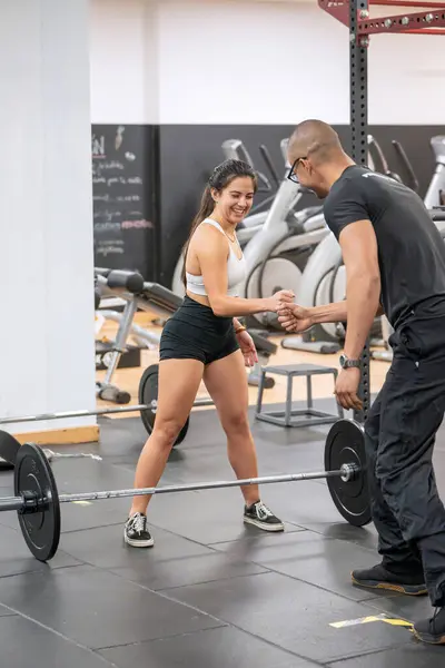 Cheerful Woman Prepares Weightlifting Session Sharing Moment Her Personal Trainer lizenzfreie Stockfotos
