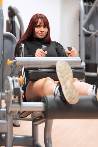 Confident Woman Red Hair Smiling While Using Leg Press Machine Stockbild