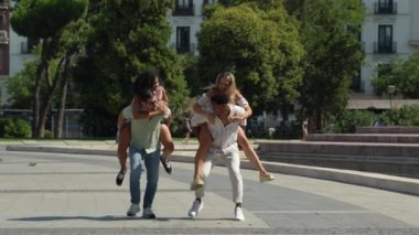 İki adam kadınları sırtında taşır, güler ve poz verir. Bir arkadaş da bu eğlenceli anı kamerayla yakalar.. 