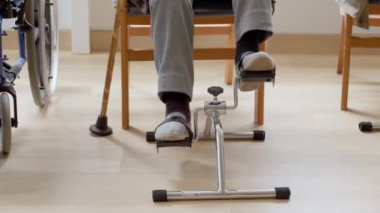Huzurevinde rehabilitasyon sırasında pedal egzersizi yapan yaşlı bir adam.