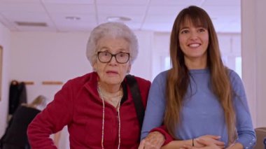 Parlak bir huzurevinde yaşlı bir kadına bakıcılık ve destek yapan hemşire şefkat ve bağlılık gösteriyor.