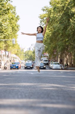 Genç bir kadın neşeyle trafiğin ortasında atlıyor, mutluluğunu ifade ediyor.
