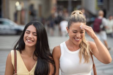 İki arkadaş gün içinde şehir caddesinde yürürken birlikte eğleniyorlar.