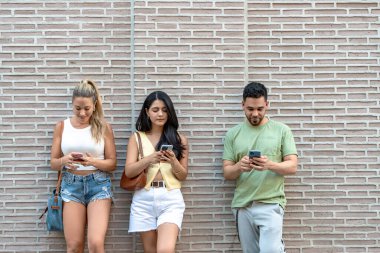 Şehirdeki üç arkadaş, akıllı telefonlara, gezintiye, kaydırmaya ve mesajlaşmaya dalmış, sürekli dijital bağlantının modern yaşam tarzını gözler önüne seriyor.
