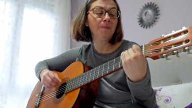 Doğal ışık ve rahat bir atmosferle çevrili rahat bir dairede akustik gitar akorları üzerinde çalışan müzisyenler.