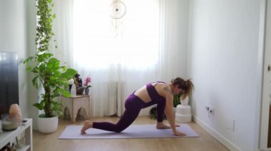 Yoga yapan kadın yavaş çekimde poz veriyor, dingin bir ortamda esneklik ve güç gösteriyor.