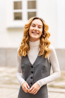 Ofis binasının önünde durup eğlenen neşeli bir iş kadınının portresi.