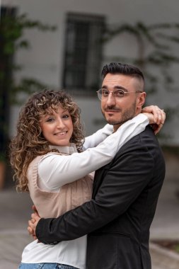 Bir şehir caddesinde birbirine sarılan genç çift, sevgi ve mutluluğu ifade ediyor.