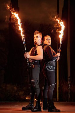 Two fire dancers holding torches during a night performance, creating a captivating spectacle clipart