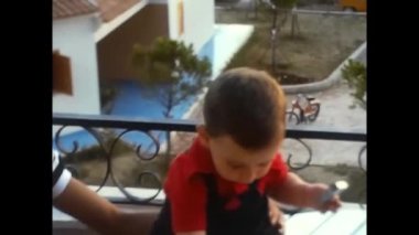 Napoli, İtalya Haziran 1980: 80 'lerde balkon masasında oturan küçük bir çocuğun videosu