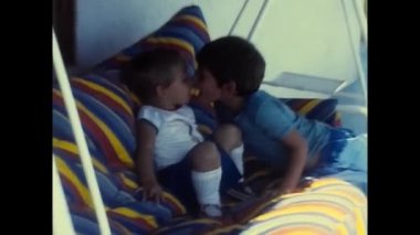 Teramo, İtalya Eylül 1980: İki çocuk kardeş 80 'lerde evin balkonunda salıncakta öpüşüyorlar.