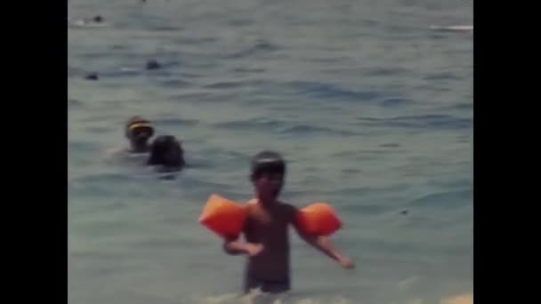 イタリアのナピリ1980年5月 赤いインフレータブル アームレストを持つ少女は80年代にビーチで楽しんでいます — ストック動画