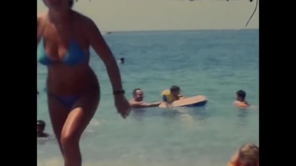 1980年 80年代 一个有着红色充气扶手的小女孩在海滩上玩得很开心 — 图库视频影像