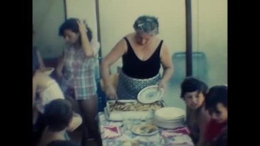 Palermo, İtalya 1970: olgun kadın 70 'lerde masada yemek ve porsiyon kesiyor
