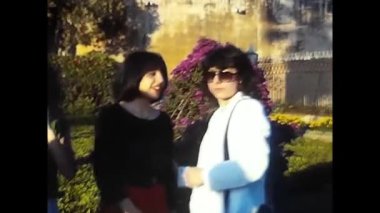 palermo, italy may 1980: happy people talking and running in a big garden in the 80s