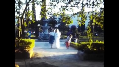 palermo, italy may 1980: shot of a family walking in a garden in the 80s