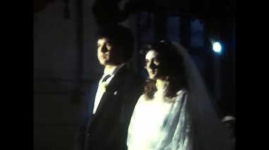 Palermo, Italy December 1980: Kneeling bride and groom on church pew during 1980s wedding ceremony.