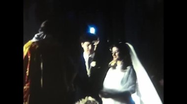 Palermo, Italy December 1980: Kneeling bride and groom on church pew during 1980s wedding ceremony.