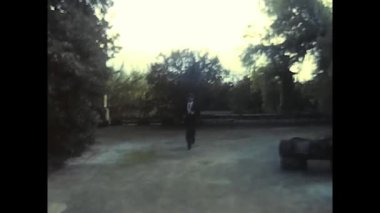 palermo,italy december 1980: happy bride and groom run and hug each other in the park in the 80s