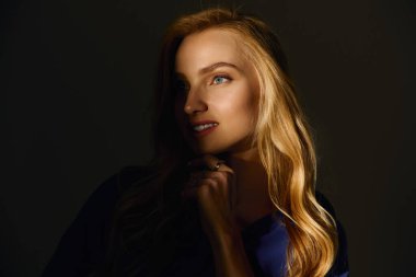 Kendinden emin bir şekilde poz veren genç bir kadın, pohpohlayıcı bir ışıkla güzellik ve tarz yayar..