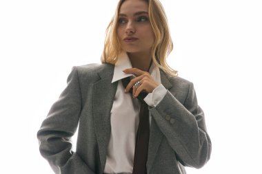 Şık giyinmiş kendine güvenen genç bir kadın zarifçe poz verir ve zarafet ve cazibe yayar..