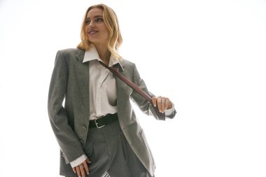 Genç bir kadın modaya uygun kıyafetiyle gösteriş yapıyor. Parlak bir ortamda ışıldıyor..