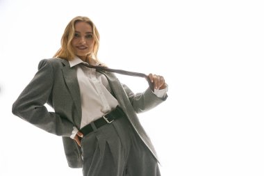 Şık giyinmiş kendine güvenen bir kadın güçlü bir duruş sergiler..