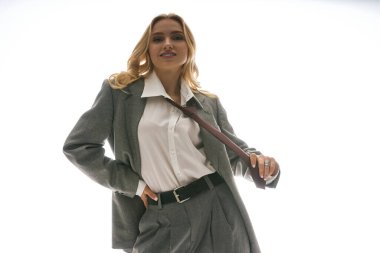 Şık giyinmiş kendine güvenen genç bir kadın, parlak bir şehir zeminine karşı maharetle poz veriyor..