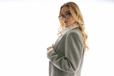 Moda kıyafetli, kendine güvenen genç bir kadın. Parlak bir arkaplanda zarafet ve tarz yayıyor.