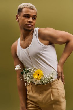 Genç bir Afrikalı Amerikalı, modaya uygun bir stüdyo ortamında canlı çiçeklerle güven içinde poz veriyor..