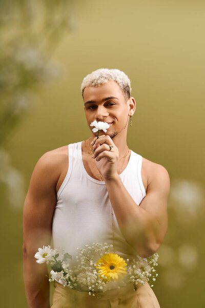 Молодой афроамериканец с модными окрашенными волосами позирует в майке, игриво держа цветок.