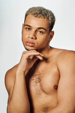 Genç siyahi bir adam kendine güvenerek poz veriyor. Stüdyoda kendine has fiziğini ve tarzını sergiliyor..