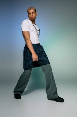 Tarz sahibi genç bir adam modaya uygun giyinmiş, saçları boyalı, modern modaya uygun poz veriyor..