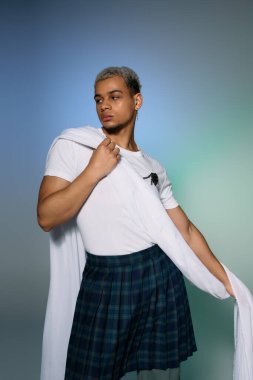 Saçları boyalı, kendine güveni tam bir genç adam modern kıyafetlerle poz veriyor, kendi tarzını yansıtıyor..