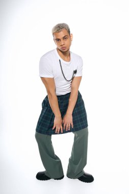 Kendine güvenen genç bir adam şık bir elbise içinde temiz bir arkaplana karşı poz verir ve bireyselliği ifade eder..