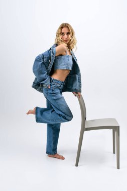 Şık, sarı saçlı bir kadın poz verirken şık bir kot giyer..