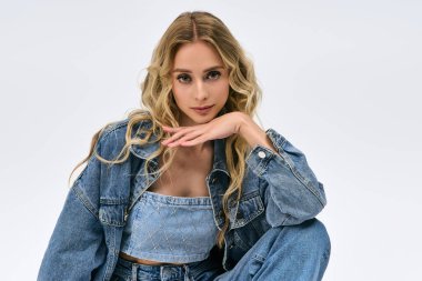 Sarışın kadın kendine güvenerek poz veriyor ve moda kot pantolonları içeride sergiliyor..