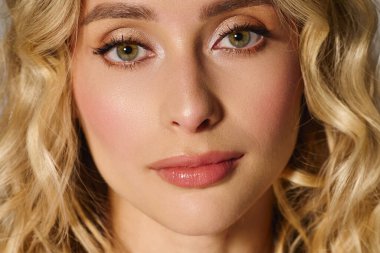 Dalgalı sarı saçlı çekici genç bir kadın renkli bir ortamda gösteriş yapıyor..