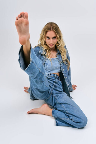 A young woman in a trendy denim outfit strikes a playful pose against a bright backdrop.