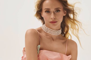 Genç kadın zarif pozlar veriyor, dalgalı sarı saçlar, gösterişli moda ve zarafet.