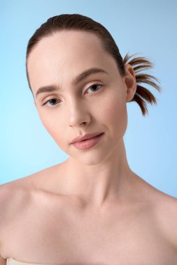 Zarif genç bir kadın narin mavi bir arka plana karşı zarif bir şekilde poz verir..